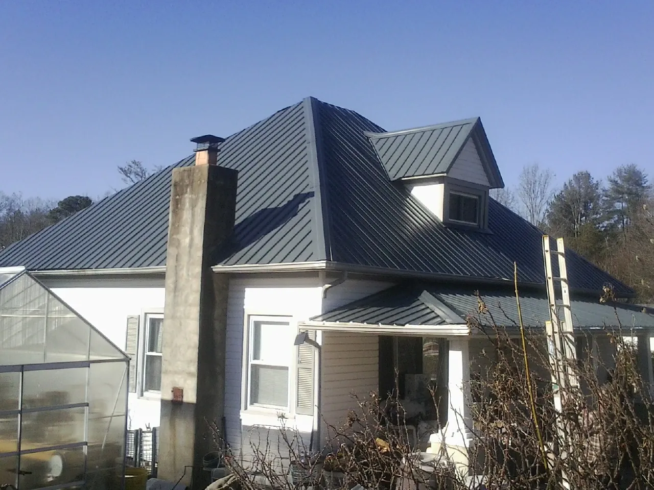 Dark blue standing seam metal roof on a white farmhouse with dormer — Slate & Tile Roof Repair by Roofing Brothers in Dunreith