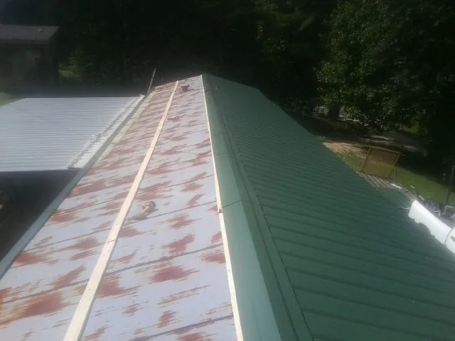 Old rusted panels beside newly installed green metal roofing — Wind Damage Roof Repair by Roofing Brothers in Dunreith