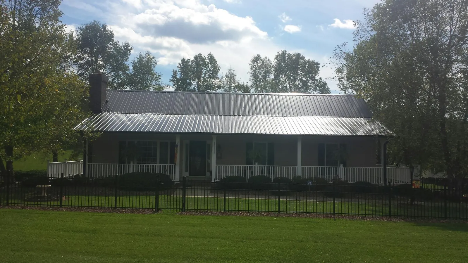 Gray metal roof on a brick ranch with a full width front porch — Gutter Guard Installation work by our crew in Dunreith
