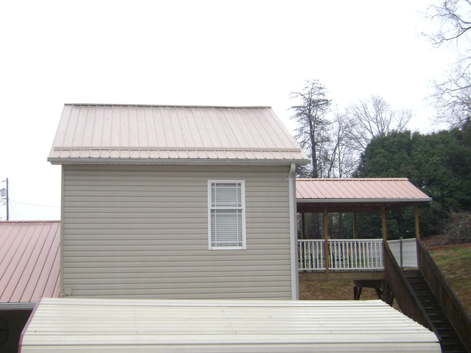 Tan metal roofs on a two story addition and attached porch, from a Roof Replacement job in Dunreith