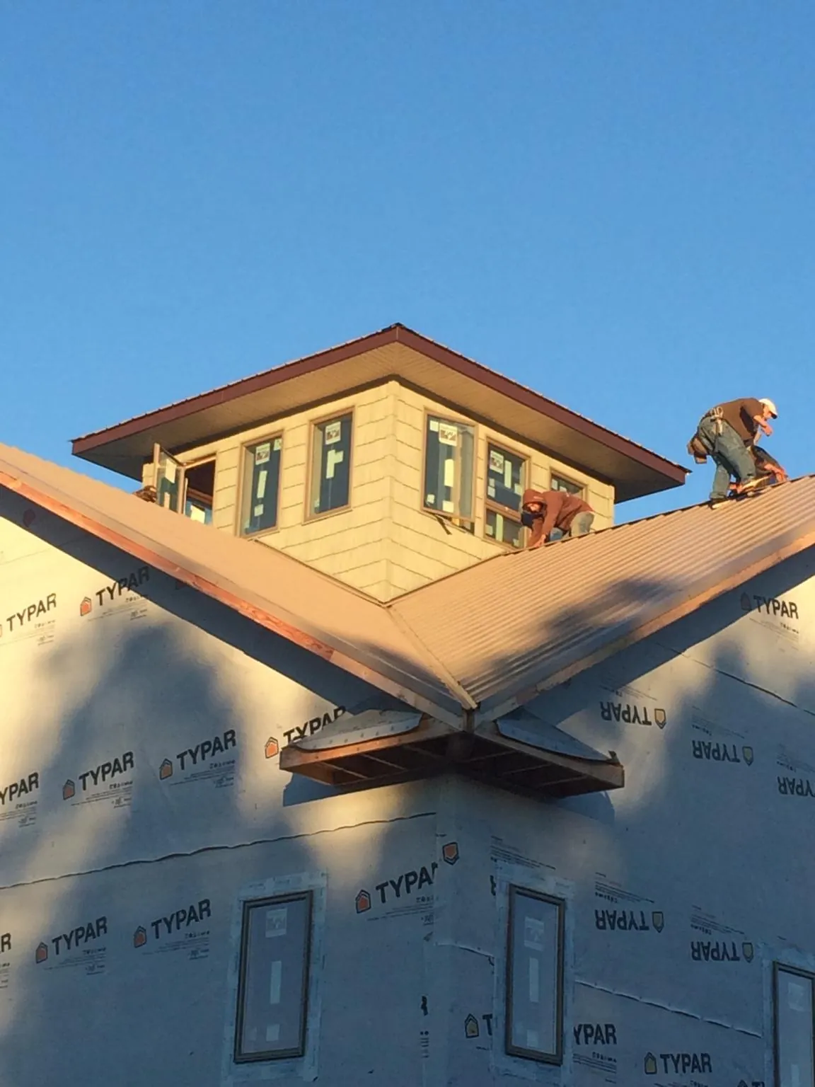 Roofers working around a rooftop cupola on a new metal roof at sunset — Roof Waterproofing in Dunreith by Roofing Brothers